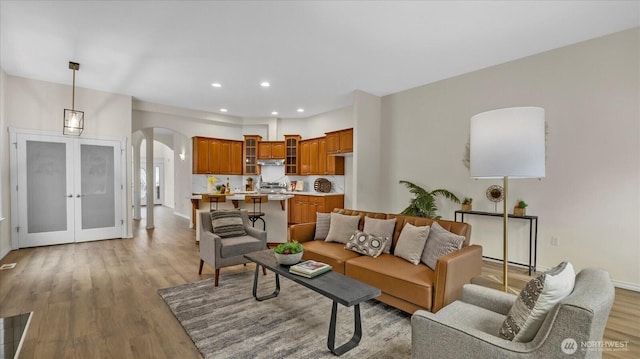 living room featuring recessed lighting, light wood-style floors, arched walkways, and french doors