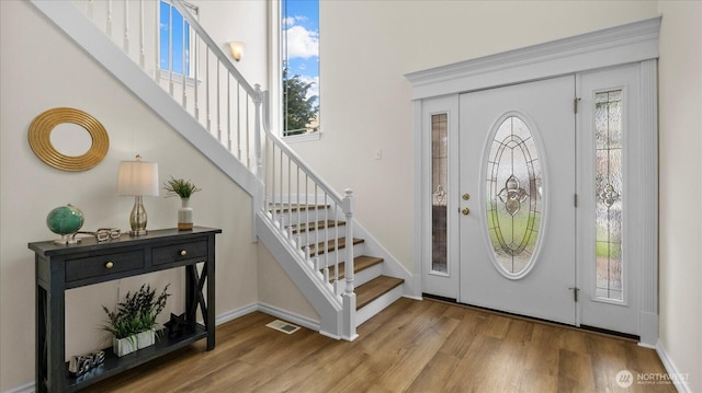 entryway featuring visible vents, stairway, baseboards, and wood finished floors