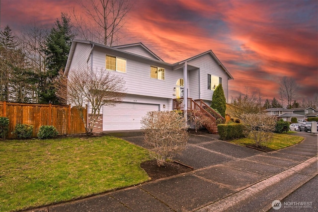split foyer home with an attached garage, a front lawn, aphalt driveway, and fence
