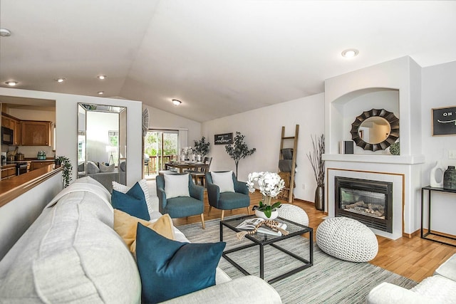 living room with recessed lighting, lofted ceiling, a tile fireplace, and light wood finished floors