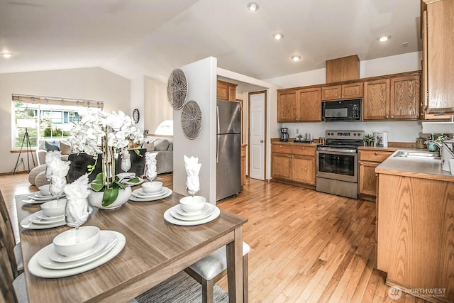 kitchen with vaulted ceiling, brown cabinets, stainless steel appliances, and a sink