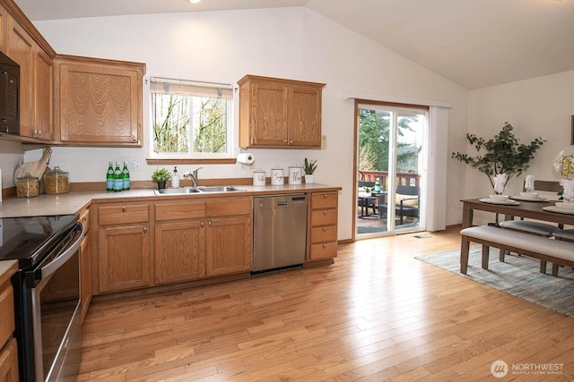 kitchen featuring brown cabinets, a sink, appliances with stainless steel finishes, light wood finished floors, and lofted ceiling