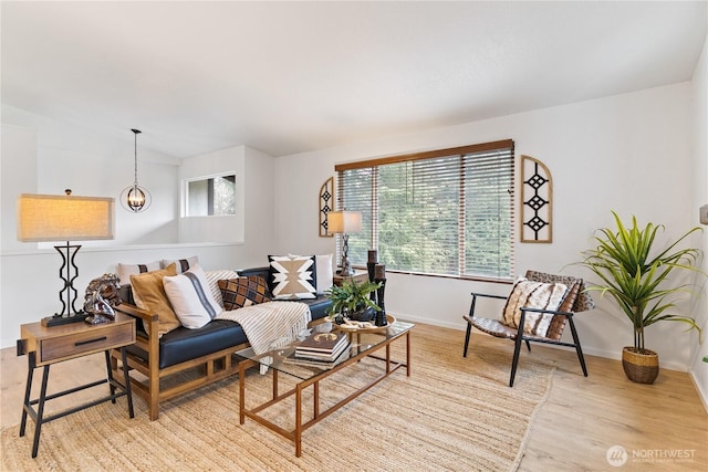 living room featuring a wealth of natural light, baseboards, light wood-style floors, and a chandelier