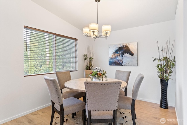 dining area with baseboards, lofted ceiling, an inviting chandelier, and light wood finished floors