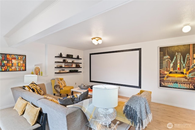 home theater featuring beam ceiling, wood finished floors, and baseboards