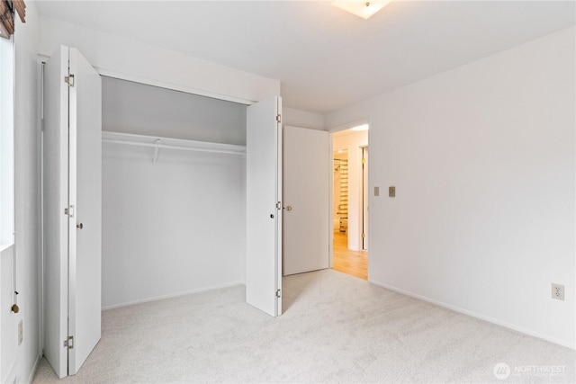 unfurnished bedroom with carpet flooring, baseboards, and a closet