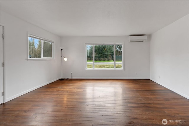 unfurnished room featuring hardwood / wood-style floors, an AC wall unit, and baseboards