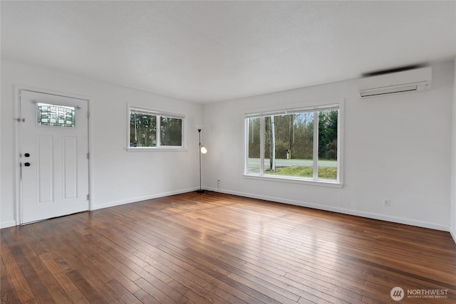 interior space with wood-type flooring, baseboards, and a wall mounted air conditioner