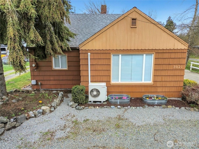 exterior space with ac unit, roof with shingles, and a chimney