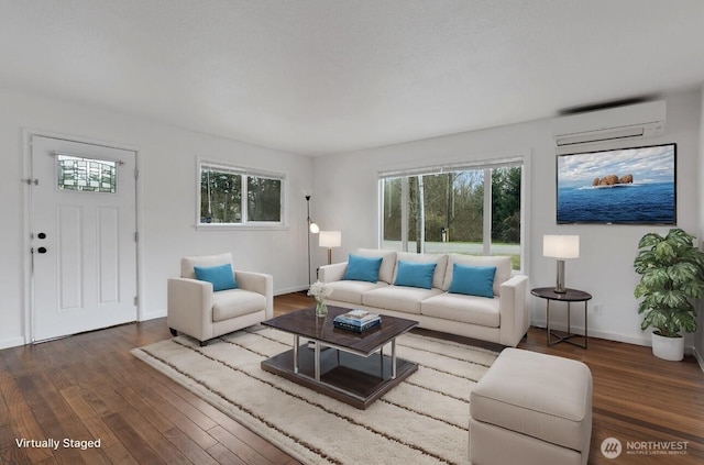 living room with an AC wall unit, hardwood / wood-style flooring, and baseboards