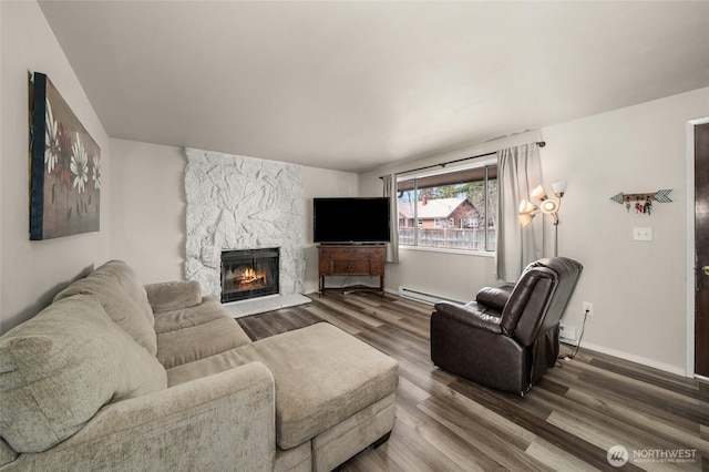 living area featuring baseboards, baseboard heating, wood finished floors, and a fireplace