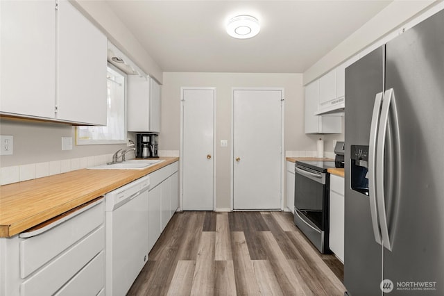 kitchen featuring a sink, light countertops, under cabinet range hood, appliances with stainless steel finishes, and white cabinetry