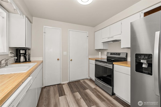 kitchen featuring under cabinet range hood, a sink, wood finished floors, stainless steel appliances, and white cabinets