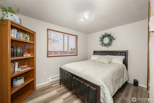 bedroom featuring wood finished floors, baseboards, and a baseboard radiator