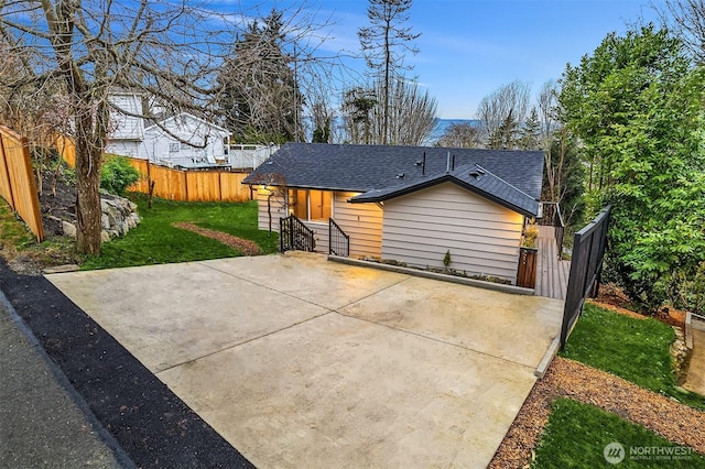 view of front of property with a patio, fence, a front lawn, and a shingled roof