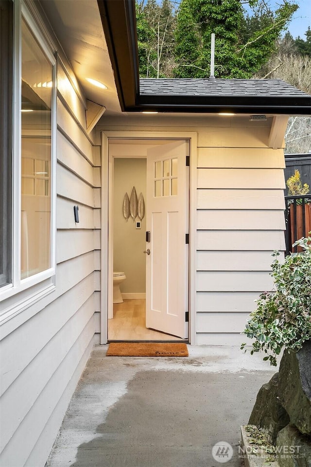 doorway to property with a shingled roof