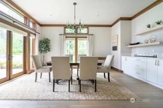 dining room with wood finished floors, baseboards, ornamental molding, french doors, and a notable chandelier