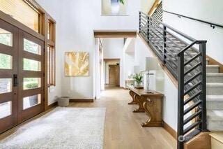 entrance foyer with french doors, baseboards, wood finished floors, and stairs