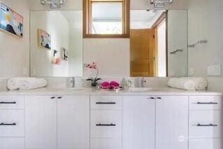 full bathroom with double vanity and a sink