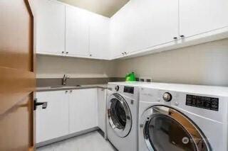 clothes washing area with cabinet space, washer and dryer, and a sink