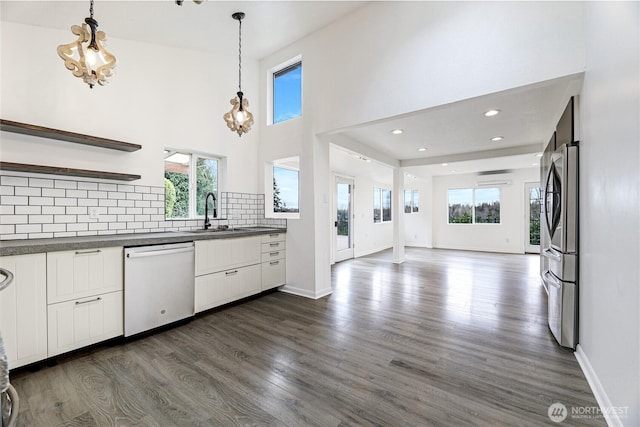 kitchen with dark countertops, a sink, dishwashing machine, freestanding refrigerator, and open shelves