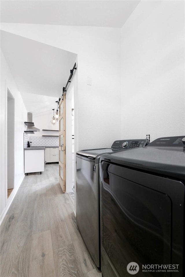 washroom featuring a barn door, laundry area, light wood-style floors, and separate washer and dryer