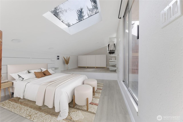 bedroom featuring lofted ceiling with skylight and wood finished floors