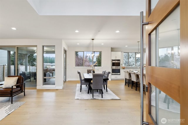 dining space with plenty of natural light, an inviting chandelier, and light wood finished floors