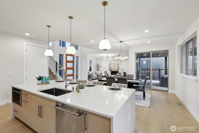 kitchen with a center island with sink, recessed lighting, a sink, light wood-style floors, and pendant lighting