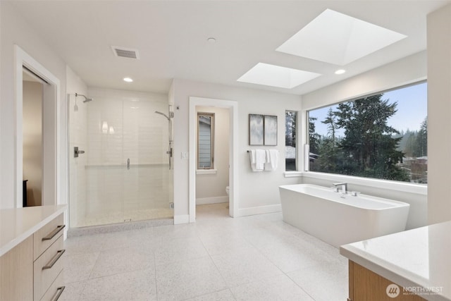 full bath featuring a skylight, baseboards, visible vents, and a stall shower