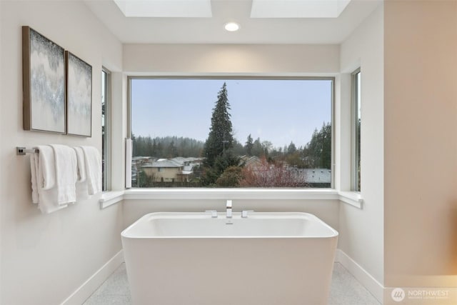 full bath with a skylight, recessed lighting, baseboards, and a freestanding tub