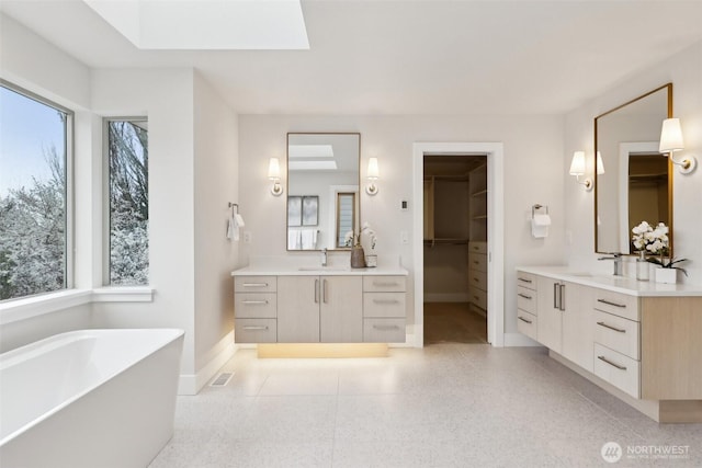 bathroom with a sink, speckled floor, baseboards, and two vanities