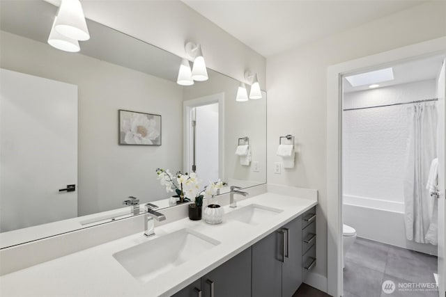 bathroom with double vanity, toilet, and a sink