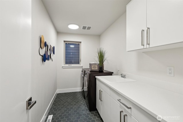 laundry room with visible vents, baseboards, washer and clothes dryer, cabinet space, and a sink