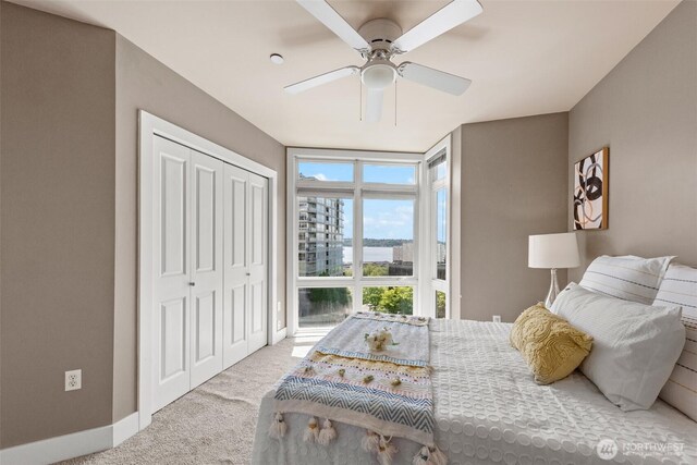 bedroom with a ceiling fan, baseboards, carpet floors, a closet, and expansive windows