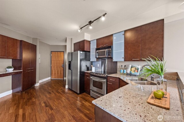 kitchen featuring a sink, light stone countertops, appliances with stainless steel finishes, modern cabinets, and dark wood-style flooring