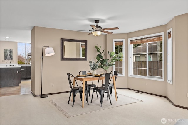 dining room with baseboards, light carpet, and ceiling fan