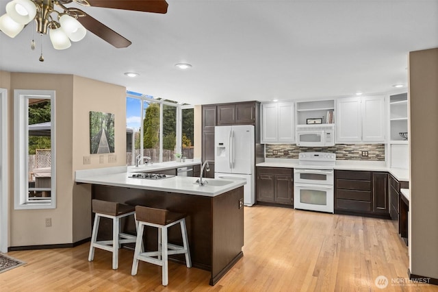 kitchen featuring white appliances, a peninsula, open shelves, and light countertops