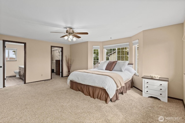 bedroom with light carpet, multiple windows, baseboards, and connected bathroom