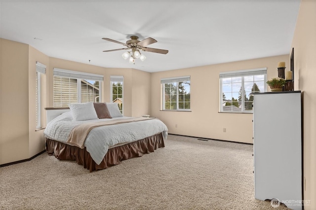 carpeted bedroom with visible vents, baseboards, and a ceiling fan