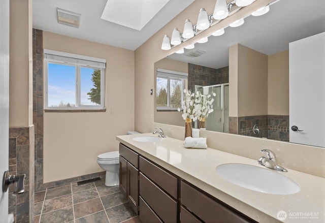 bathroom with a shower stall, a skylight, visible vents, and a sink