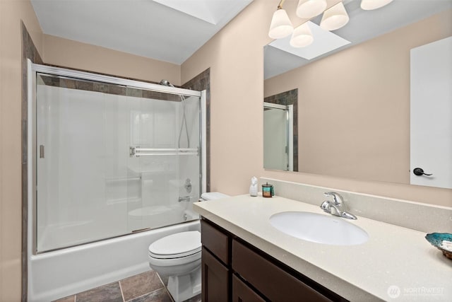 full bath featuring a skylight, toilet, vanity, and bath / shower combo with glass door