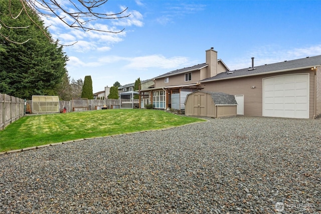 view of yard featuring an outdoor structure, an attached garage, a fenced backyard, and a storage unit