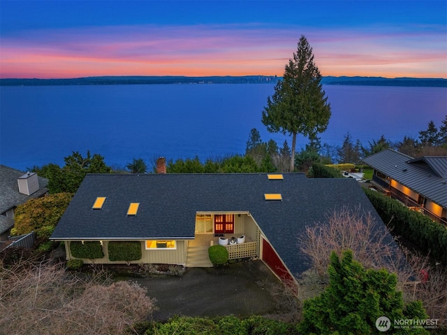 aerial view at dusk featuring a water view