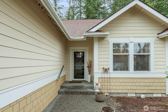 view of exterior entry featuring roof with shingles and crawl space