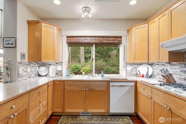 kitchen with white appliances, visible vents, light brown cabinetry, a sink, and under cabinet range hood