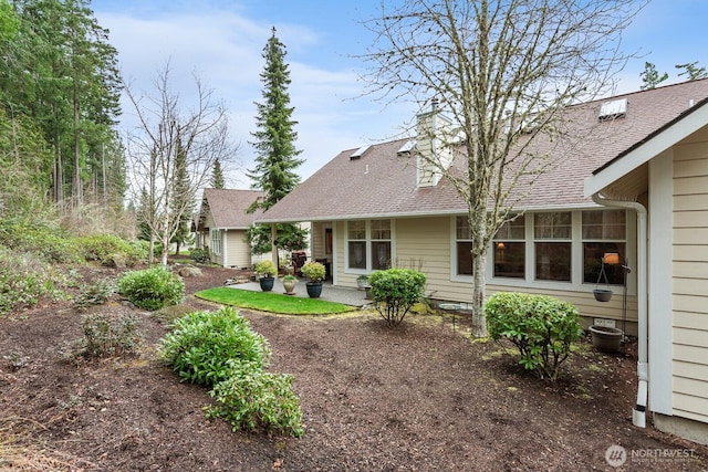 back of property featuring a patio area, a chimney, and a shingled roof