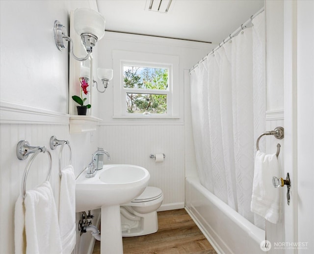 full bath with visible vents, a wainscoted wall, toilet, wood finished floors, and shower / bathtub combination with curtain