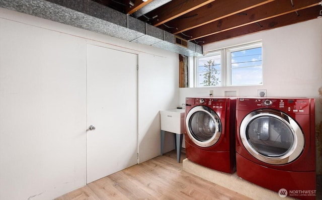 laundry area with washing machine and clothes dryer and light wood-style floors