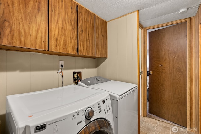 laundry area with a textured ceiling, cabinet space, and washing machine and clothes dryer